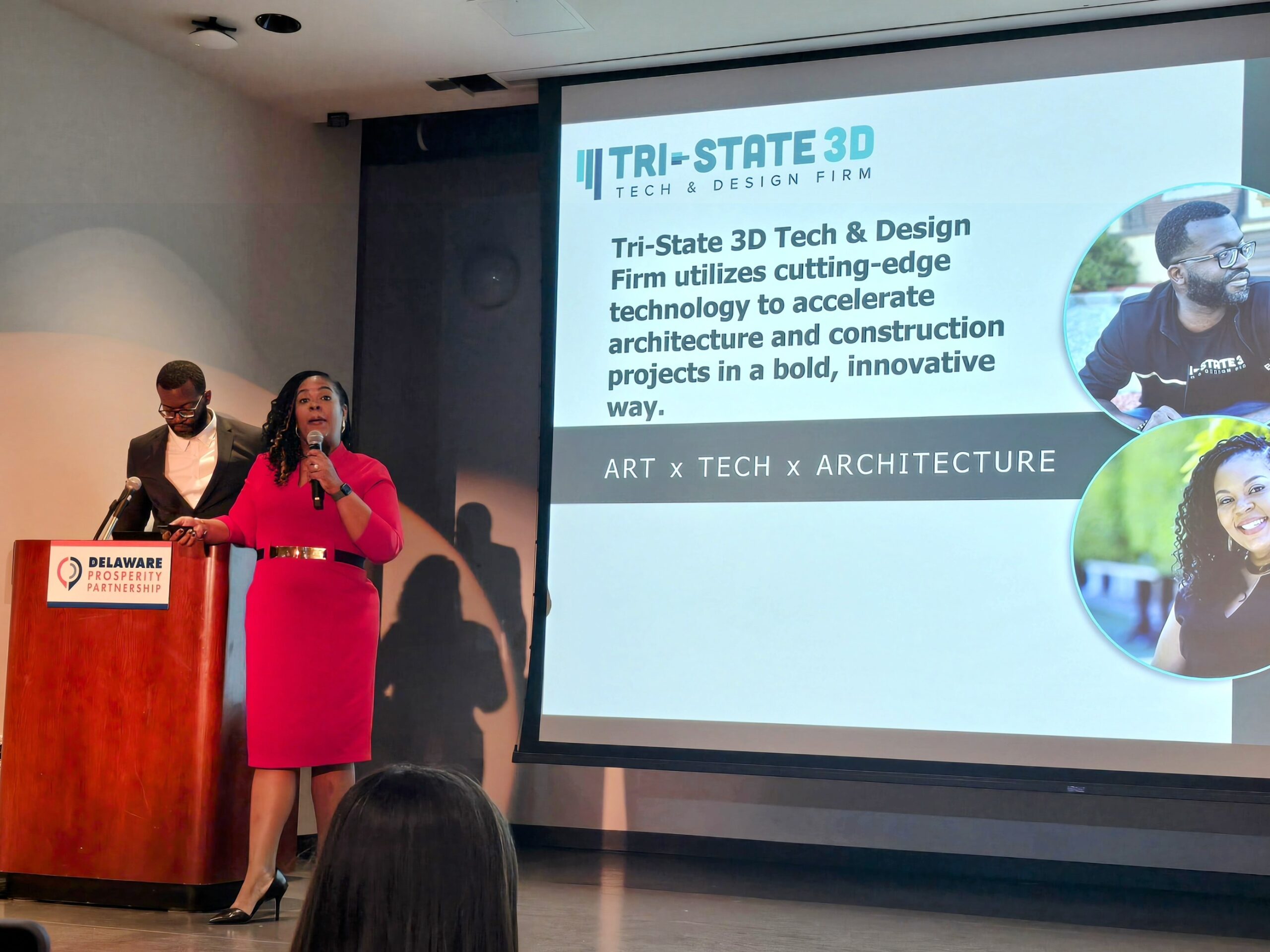 Two people stand in behind a podium giving a presentation