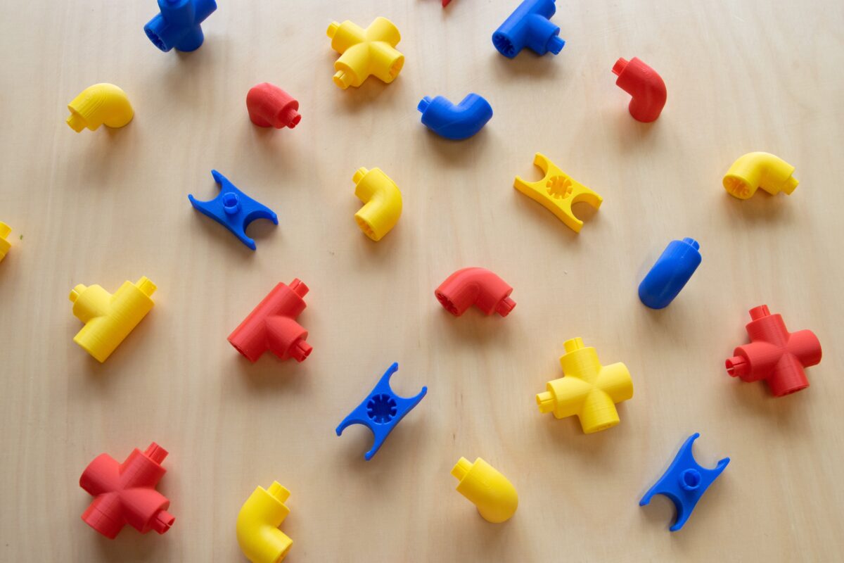 Red, blue and yellow Plexo pieces on a beige wood table.