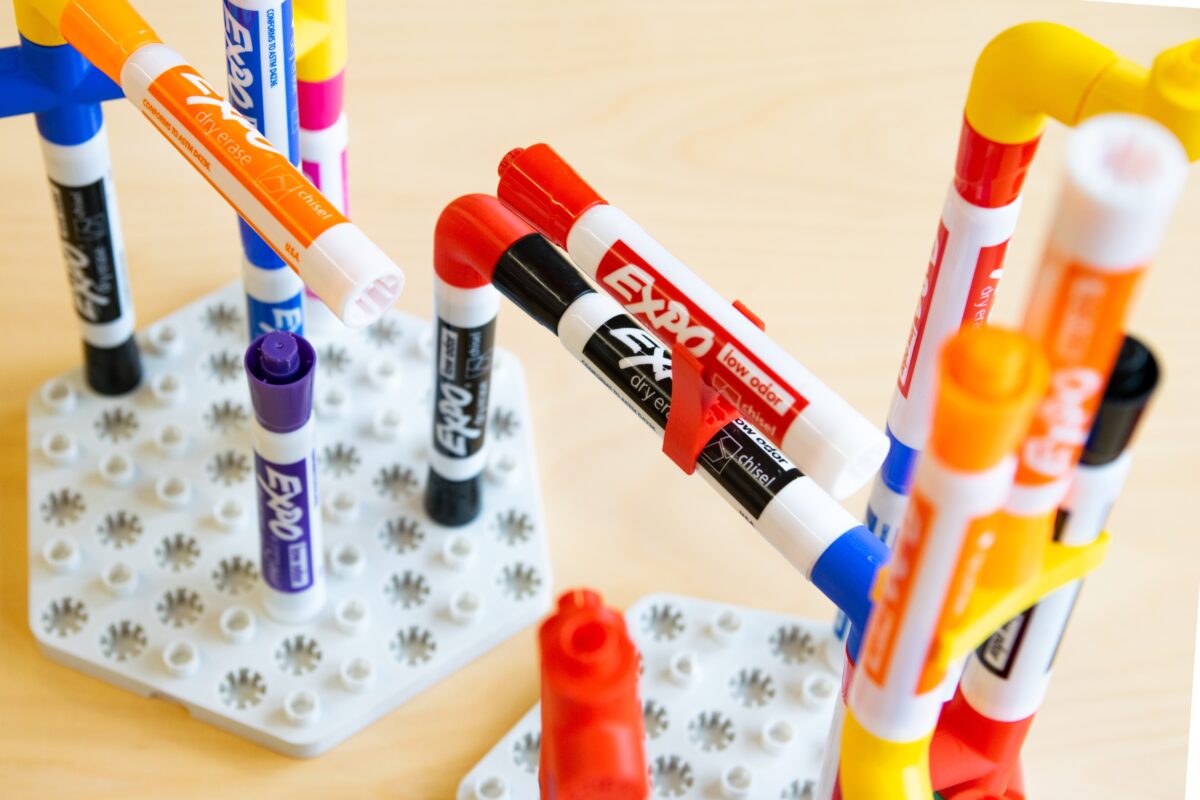 Multicolored Expo dry-erase markers linked together by red, yellow and blue Plexo pieces.