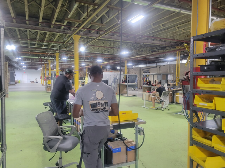 People work in manufacturing space with green floor and yellow materials