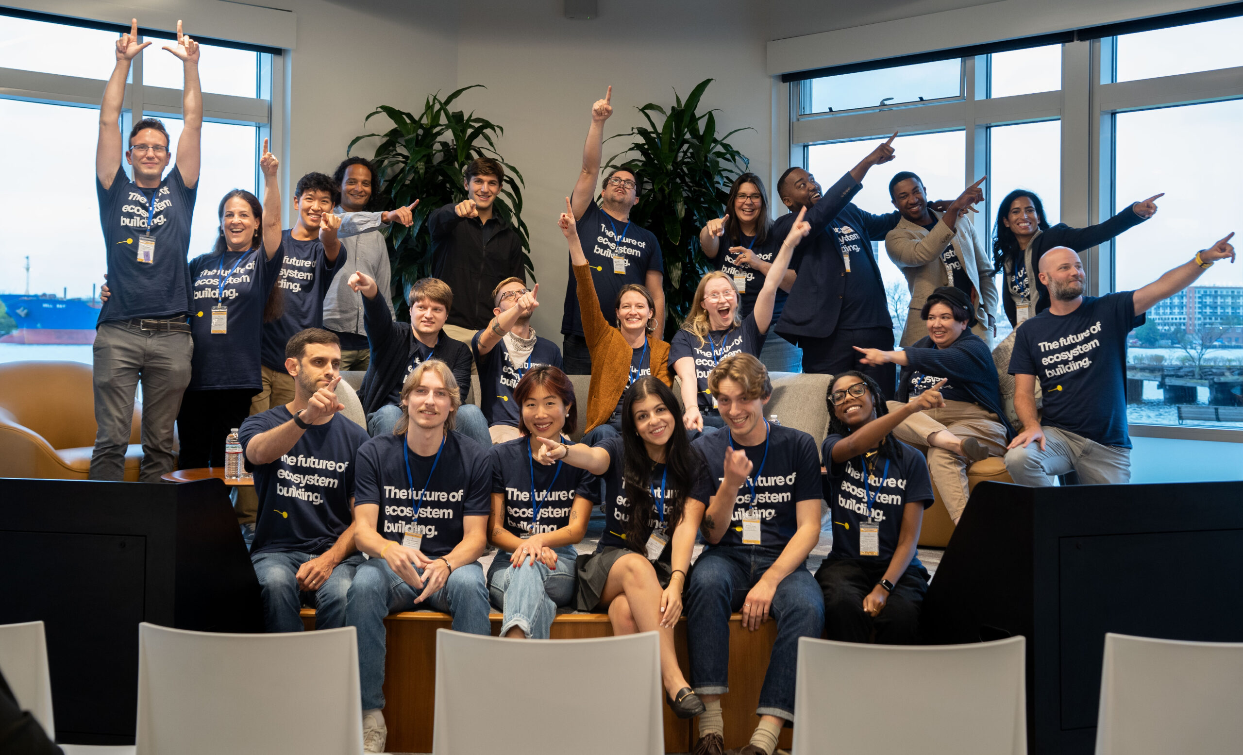 A group of people in navy t-shirts with white text pointing in different directions.