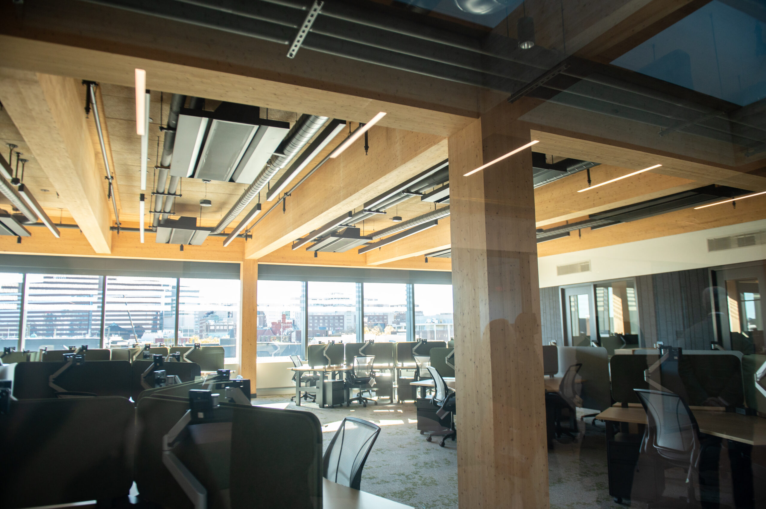 A modern office space with open seating, large windows, and exposed ceiling beams.