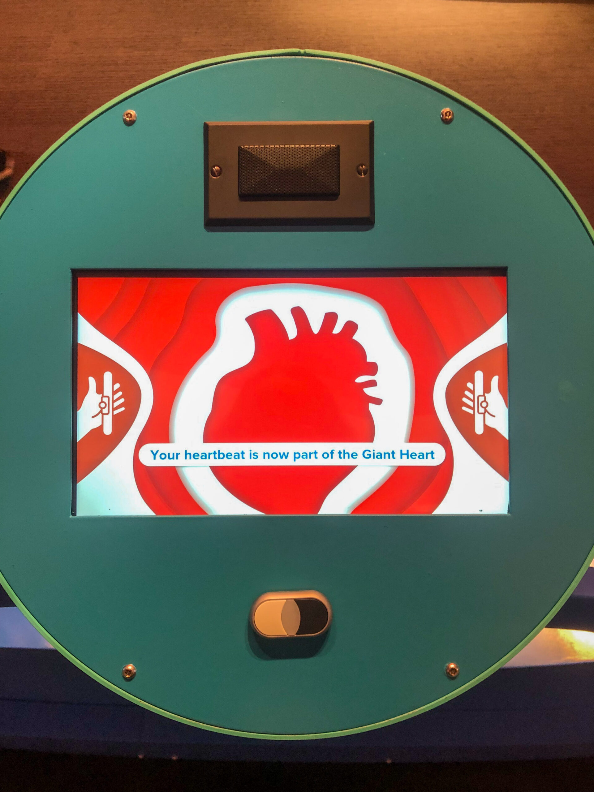 Interactive exhibit with a screen displaying a heart graphic and the message "Your heartbeat is now part of the Giant Heart.