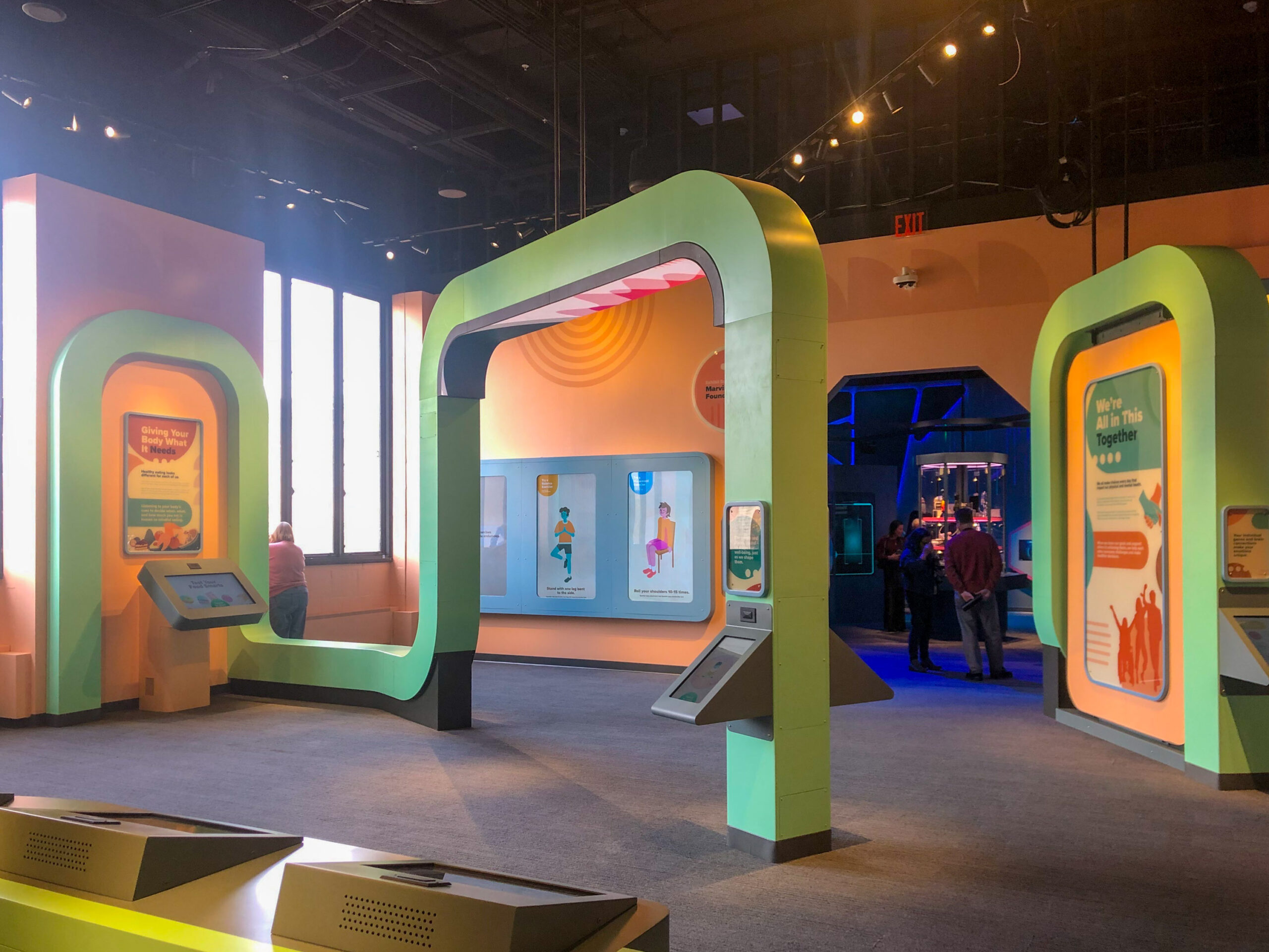 Interactive museum exhibit with colorful displays and informational panels. Visitors are viewing the exhibits in a brightly lit room.